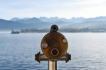 a telescope on the pier with alps view