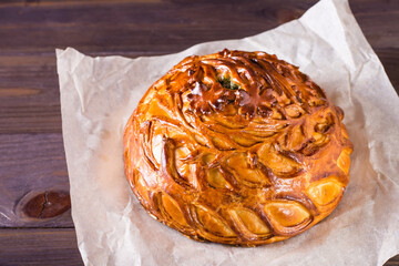 Homemade hearty kurnik pie with chicken, potatoes and rice on parchment. © elenarui