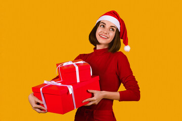 Happy young woman in Santa hat holding xmas presents