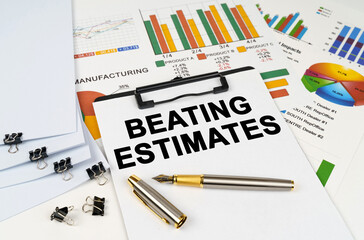 On the table among financial graphs and charts lies a tablet with the inscription - Beating Estimates