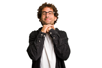 Young curly smart caucasian man cut out isolated keeps hands under chin, is looking happily aside.