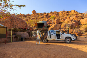 Typical 4x4 rental car in Namibia at the campground. Mowani, Damaraland, Namibia. - obrazy, fototapety, plakaty