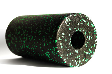 A black green massage foam roller isolated on a white background. Close-up. Foam rolling is a self myofascial release technique. Concept of fitness equipment.