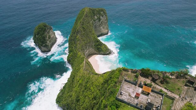 Aerial shot of Kelingking beach and many tourists at ancient temple on edge of cliff on tropical island Nusa Penida.