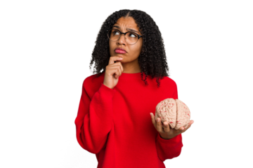 Young african american woman holding a brain model isolated looking sideways with doubtful and skeptical expression.