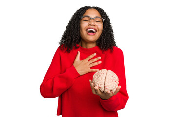 Young african american woman holding a brain model isolated laughs out loudly keeping hand on chest.