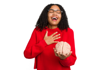 Young african american woman holding a brain model isolated laughs out loudly keeping hand on chest.