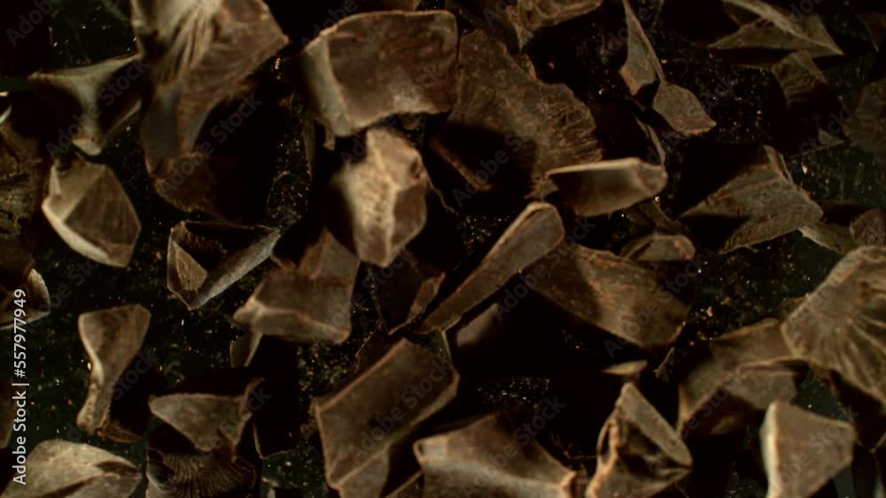 Poster super slow motion of rotating group of raw chocolate pieces. super fast camera motion. filmed on hig