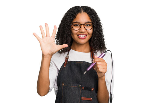 Young african american manicurist woman holding an electric file drill isolated smiling cheerful showing number five with fingers.