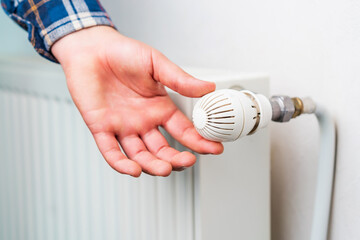 Hand on the faucet or temperature regulator on the radiator of the heating system, selective focus. Background