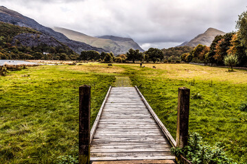 Wooden trail to the field near mountains in autumn light