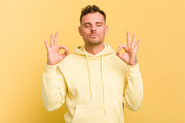 Young caucasian handsome man isolated on yellow background relaxes after hard working day, she is performing yoga.