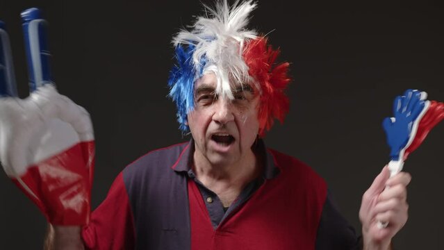 An elderly French man with dyed hair in the color of the French flag with a mohawk on his head supports his sports team. A football fan at the stadium rejoices at the victory of his team
