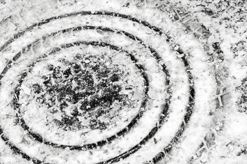 Fototapeta na wymiar Round manhole cover is under a layer of snow