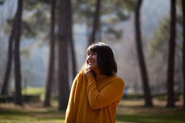 Young beautiful woman in yellow sweater enjoying spring in forest and smiling