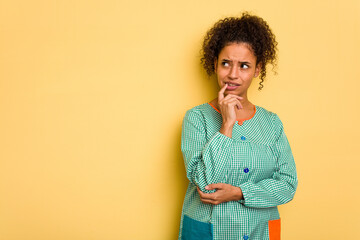 Young Brazilian child education teacher isolated relaxed thinking about something looking at a copy space.