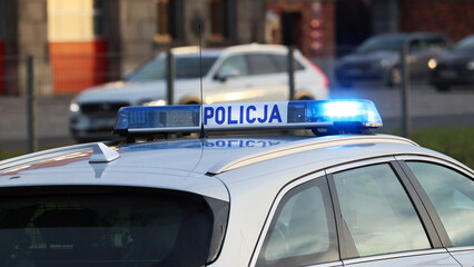 Incydent policji  w mieście. - Sygnalizator błyskowy niebieski na dachu radiowozu policji polskiej drogowej.  - obrazy, fototapety, plakaty