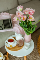 Home cozy office. Work at home. Spring decor. Knitted blanket, bouquet of tulips, hot tea, laptop. Freelance.