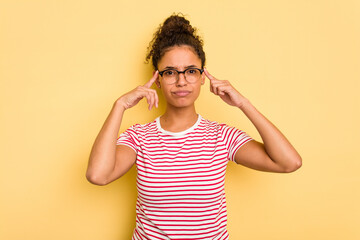 Young Brazilian curly hair cute woman isolated on yellow background focused on a task, keeping...