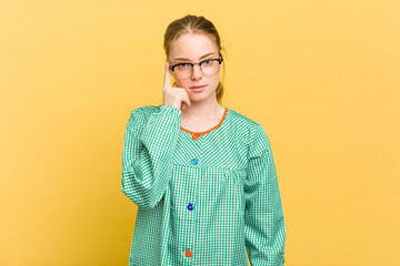 Young caucasian child education teacher isolated on yellow background pointing temple with finger, thinking, focused on a task.