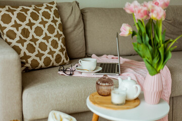 Home cozy office. Work at home. Spring decor. Knitted blanket, bouquet of tulips, hot tea, laptop. Freelance.