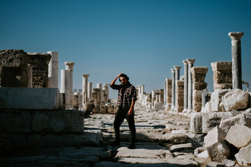 Young handsome man traveler exploring ancient Laodikeia city under cloudless blue sky