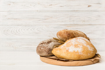 Freshly baked bread on cutting board against white wooden background. perspective view bread with copy space