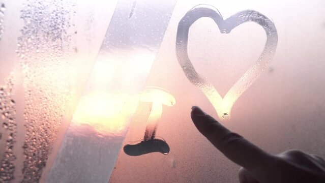 writing i love you on wet window. beautiful sunset gradient.