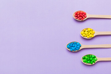 Obraz na płótnie Canvas delicious colorful sweet candies on spoon on colored background . Confectionery decor top view with copy space