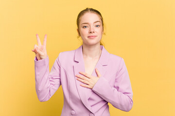 Young caucasian redhead woman isolated on yellow background taking an oath, putting hand on chest.