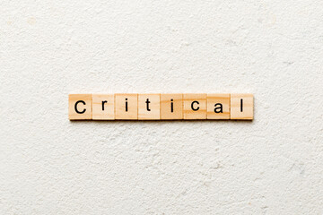 critical word written on wood block. critical text on table, concept