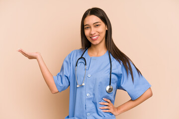 Young nurse colombian woman isolated showing a copy space on a palm and holding another hand on waist.