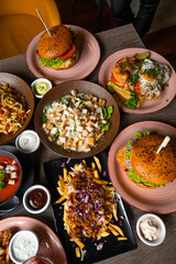 Vertical photo various of tasty junk greasy food on wooden table. BBQ service, customer order. Opening cafe, season menu