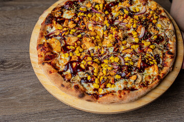 Delicious, savory, palatable Italian pizza presented on plate on wooden table. Chicken bbq, barbecue with sauce and corn