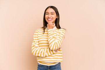 Young colombian woman isolated on beige background smiling happy and confident, touching chin with hand.