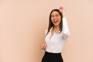 Young colombian woman isolated on beige background cheering carefree and excited. Victory concept.