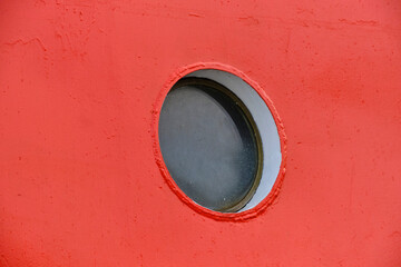 Ship round porthole red background ship hull paint.