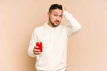 Young latin man holding a cola refreshment isolated being shocked, she has remembered important...