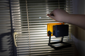 Blackout. Girl holds a bright flashlight in her hand against the background of a window