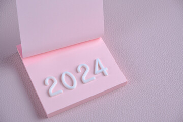 Year 2024 is laid out in white numbers pink sheet.Concept time and new year.