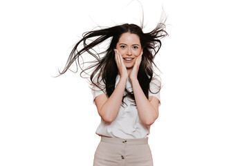Excited brunette Italian young woman with fluttering hair in casual touching cheeks by hands in...