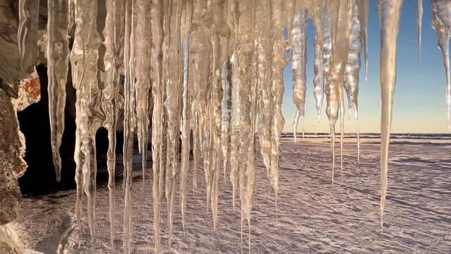 Frozen winter lake Baikal, Siberia, Russia. Ice icicles and blocks in the rocks, grottoes and caves at dawn. Natural background of cold ice. Winter abstract background. High quality 4k footage