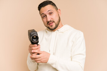 Adult latin man recording with a vintage camera isolated