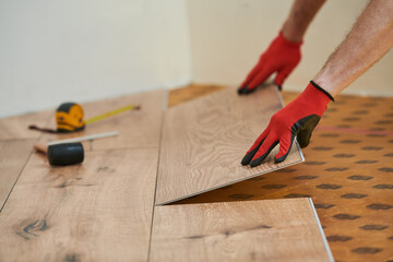 vinyl floor installation. Close-up hands of worker at home flooring renovation.
