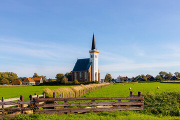 Typical landscape of Texel island, Small village and picturesque church (Hervormde kerk van Den Hoorn) on the green grass meadow polder, A little town on the wadden islands, North Holland, Netherlands - obrazy, fototapety, plakaty