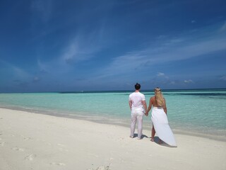 White dressed Honeymoon couple on the Malediven beach with White sand and blue ocean, Hochzeitsreise, Flitterwochen, Brautpaar am traumhaften Strand