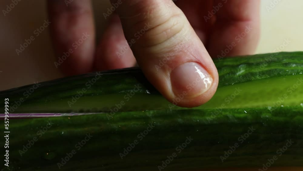 Poster hand with knife cuts cucumber on board