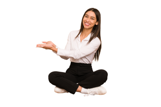 Young colombian woman sitting on the floor isolated holding a copy space on a palm.