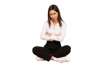 Young colombian woman sitting on the floor isolated frowning face in displeasure, keeps arms folded.