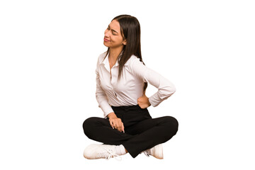 Young colombian woman sitting on the floor isolated suffering a back pain.